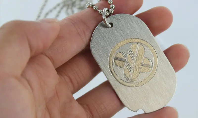 A person holding a dog tag with a symbol on it.