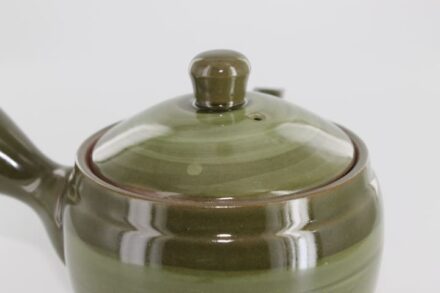 A close up of the lid on a green ceramic container.