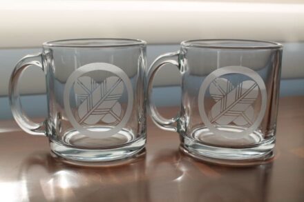 Two clear mugs sitting on top of a wooden table.