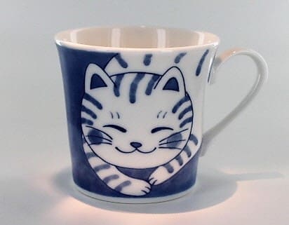 A cat mug with the image of a smiling kitten.